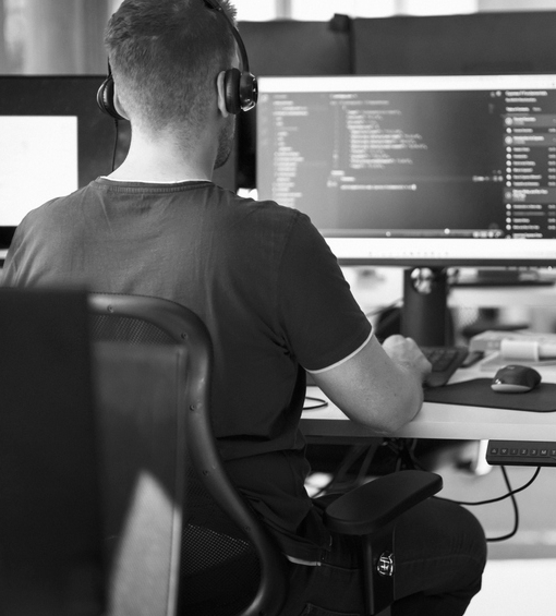 AI security engineer sitting at his desk and reviewing code on his computer